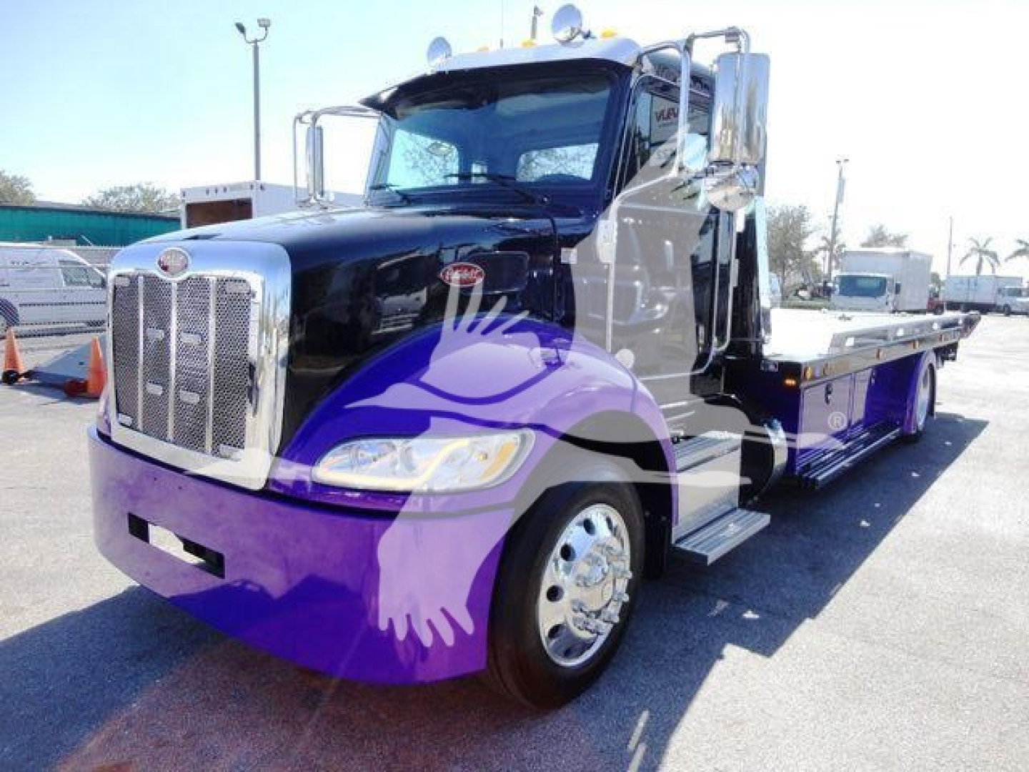Peterbilt 337 rollback truck in black with chrome grille and titanium flatbed, front-right view showing large headlight, side mirrors, and dual rear wheels.