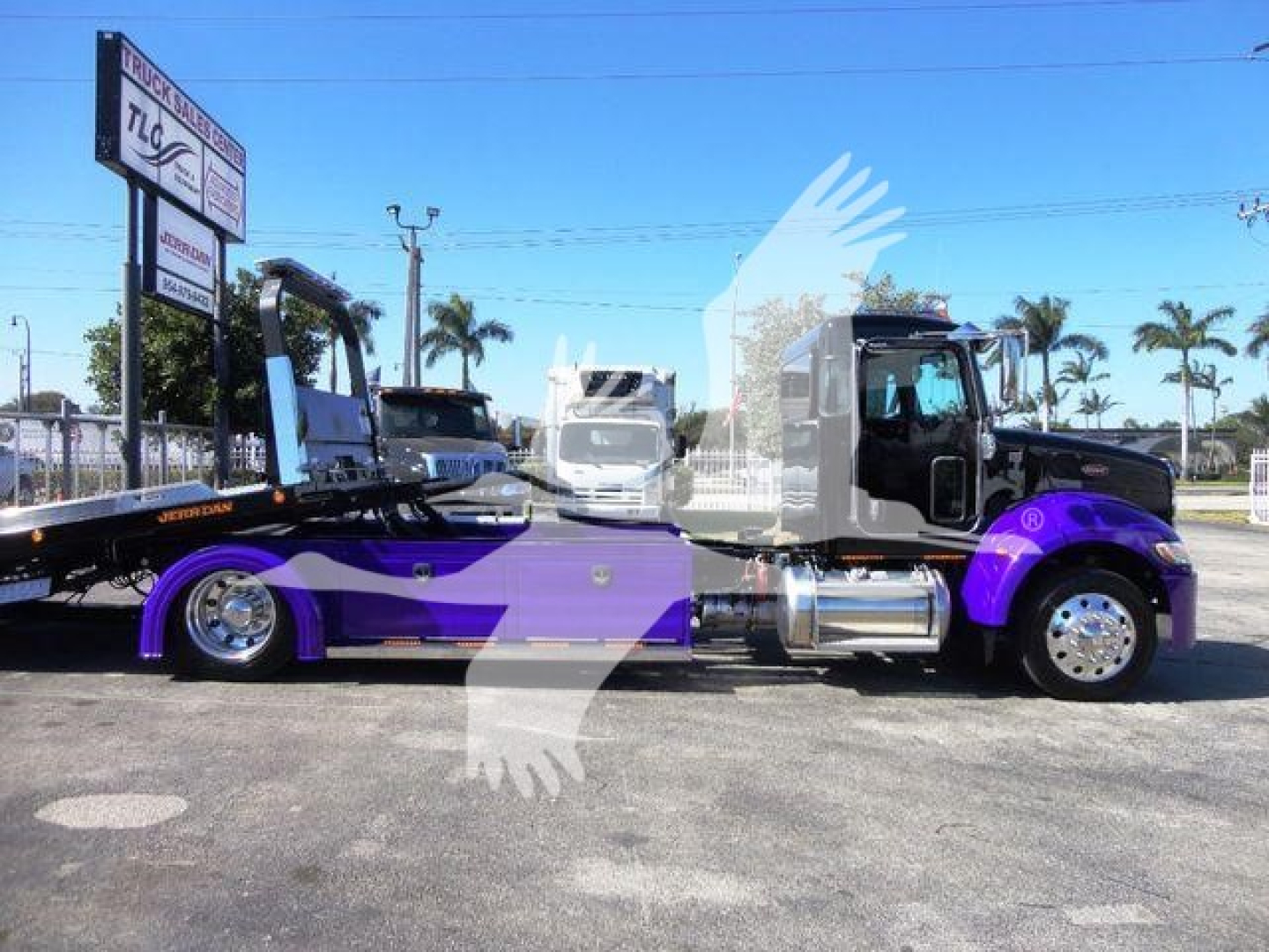 Peterbilt 337 rollback truck in side profile view with purple and black accents, chrome fuel tanks, and a flatbed rollback. Stock sign on lot in background.