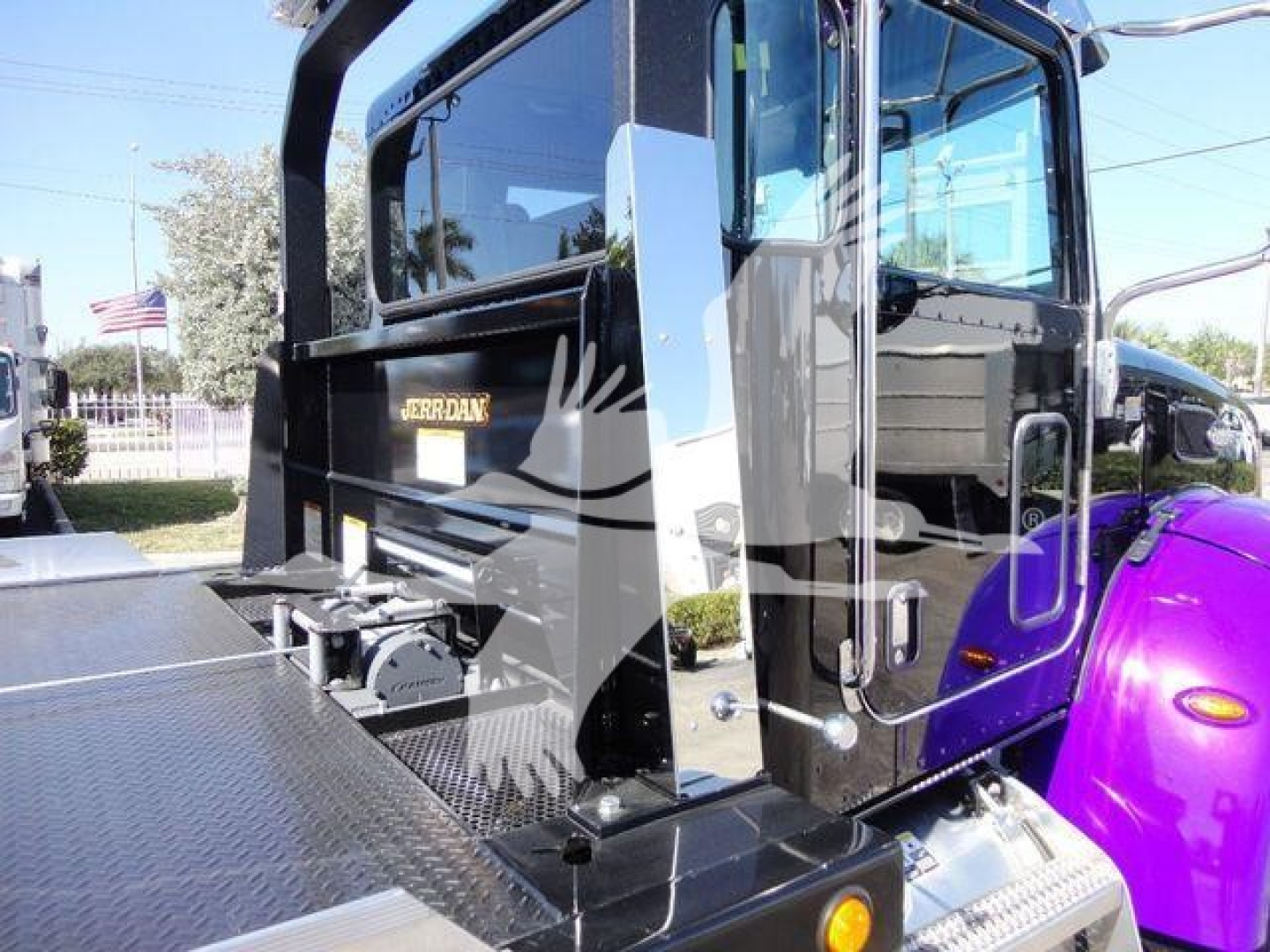 Peterbilt 337 rollback truck with black cab, purple fender, and diamond plate platform; side door and step visible; JORDAN branding on rear panel.