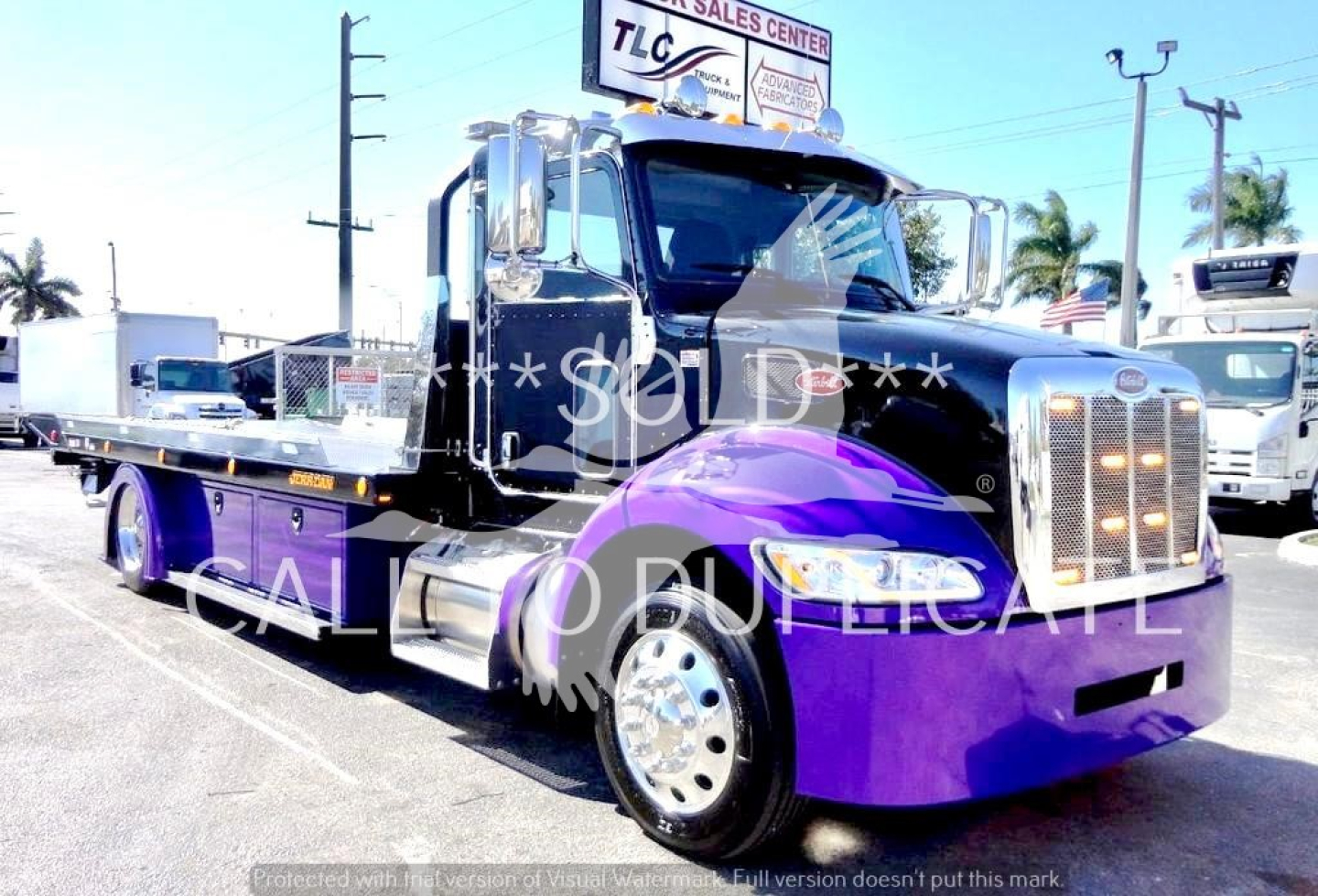 Peterbilt 337 rollback truck in purple and black showing chrome grille and extended flatbed