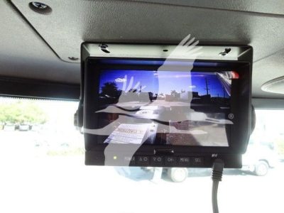 In-cab monitor screen showing multimedia display and control panel mounted under overhead area of Peterbilt 337 dash; screen shows distorted reflection and a lot of glare.