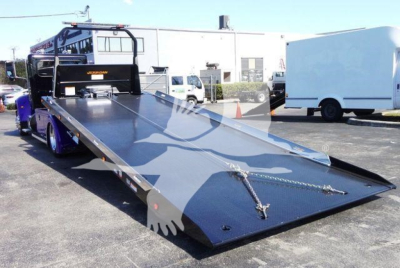 Truck bed tilt with low-angle view showing a Peterbilt 337 rollback truck and hydraulic ramps.