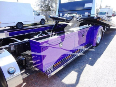 Peterbilt 337 rollback tow truck with purple tool storage box and hydraulic winch, side view showing long flatbed and chrome steps.