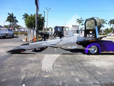 Peterbilt 337 rollback truck with a lowboy trailer attached in a parking lot.
