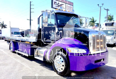 Peterbilt 337 rollback truck in purple and black showing chrome grille and extended flatbed