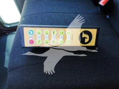 Panel with numerous circular symbols and a yellow-black sticker placed on a dark seat.