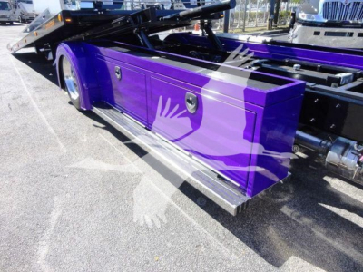 Truck toolbox side view on a purple Peterbilt 337 rollback unit showing storage compartments and metallic steps