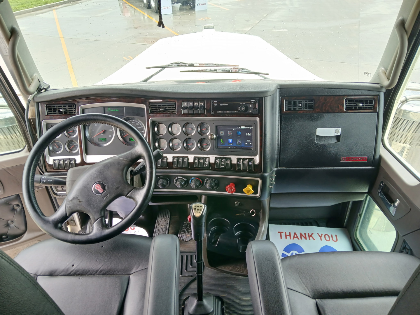 Kenworth W900L interior cab dashboard and steering wheel view, with center console gauges and controls visible.