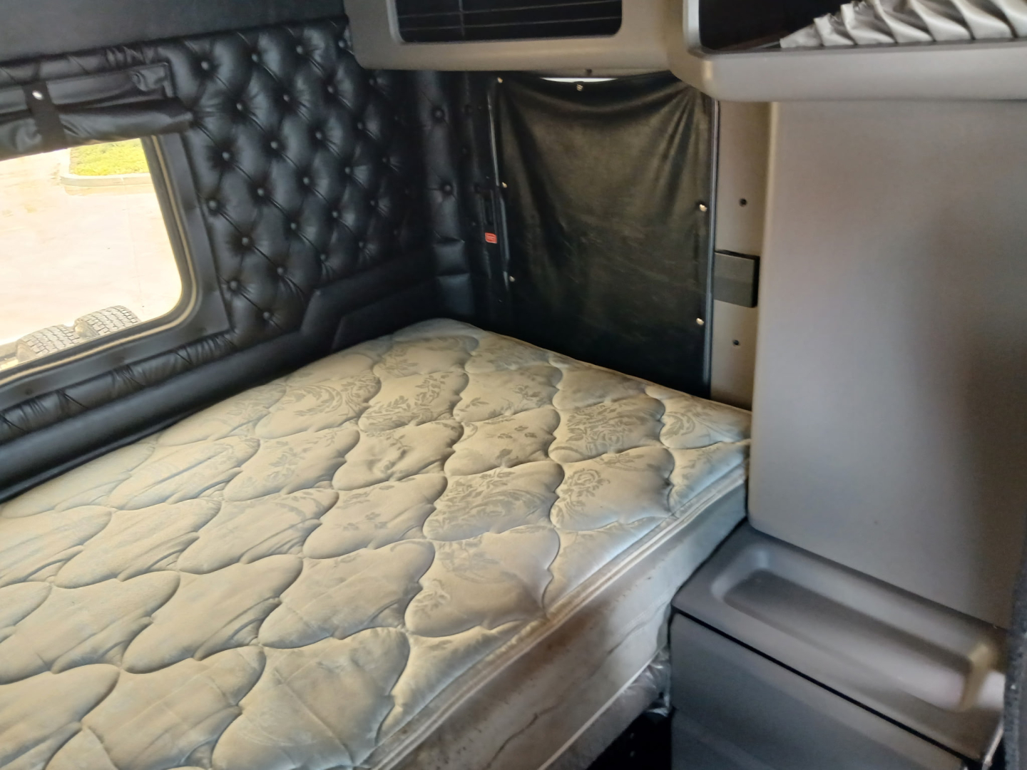 Kenworth W900L cab interior showing sleeper with padded quilted wall and bunk mattress.