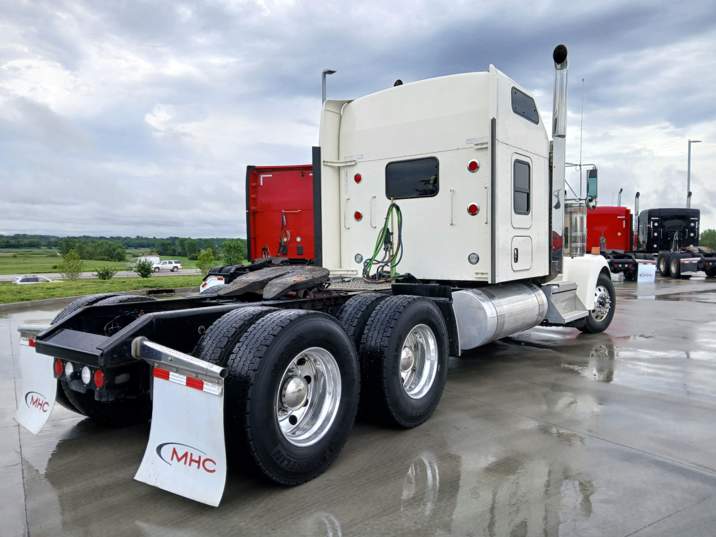 Kenworth W900L tractor rear view showing fuel tanks and dual rear axles with mud flaps