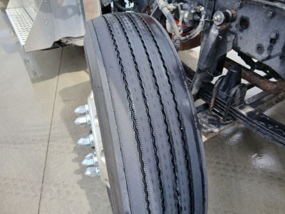 Kenworth W900L front wheel and suspension view showing steer tires and hub studs