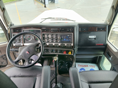 Kenworth W900L interior cab dashboard and steering wheel view, with center console gauges and controls visible.