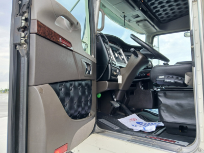 Kenworth W900L truck interior door panel and dashboard area visible; beige and brown interior; step plate; driver seat area; partial floor mats; dashboard with steering wheel
