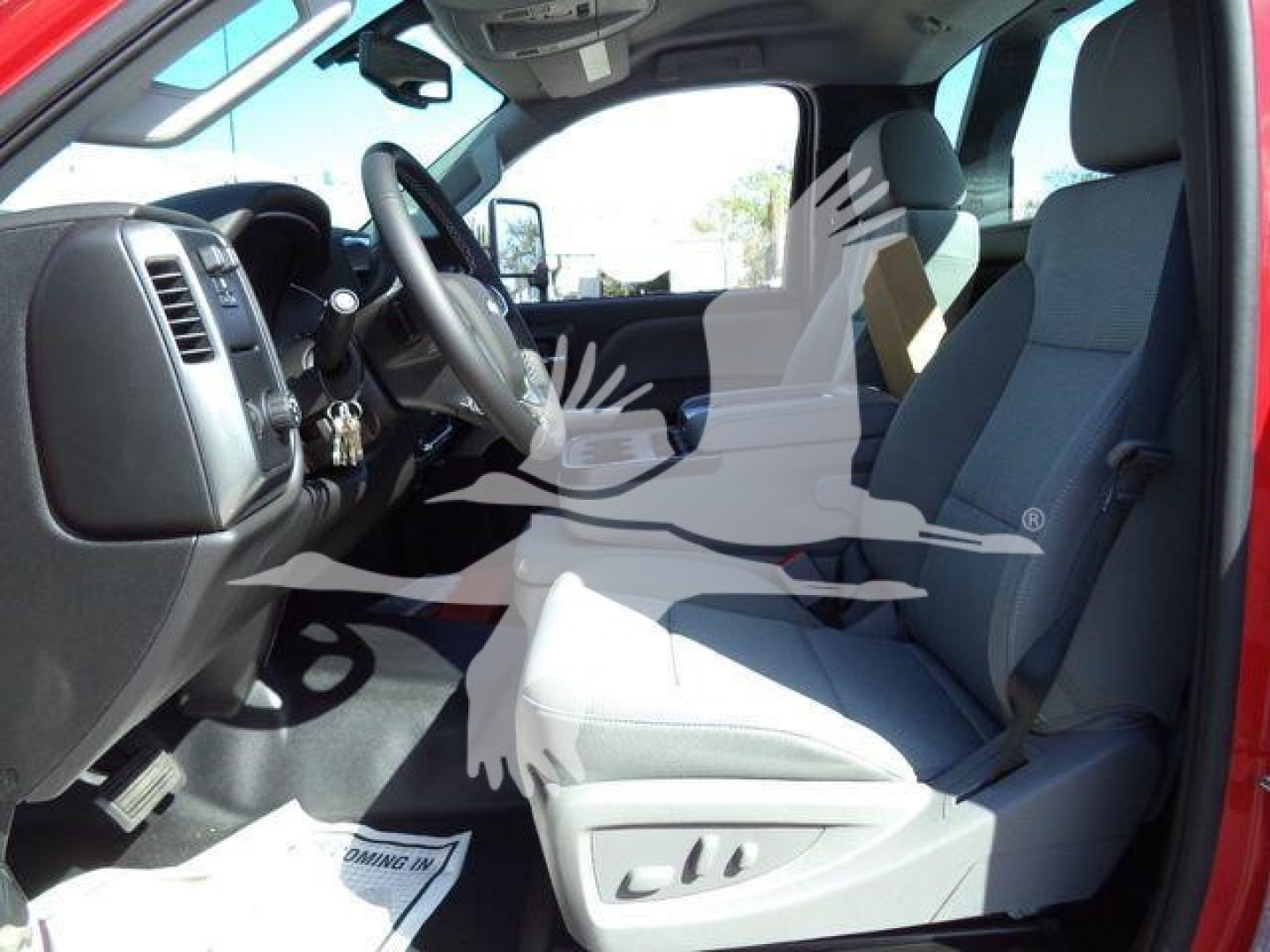 Truck interior showing driver and passenger seats, steering wheel, dashboard; text 'Coming In' on floor mat; no other legible labels visible.