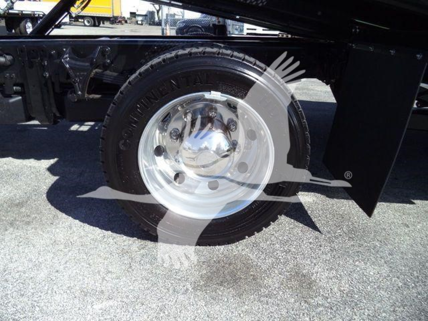 Truck wheel showing alloy hubcap and Continental tire; undercarriage and frame visible with black paint and chassis components.