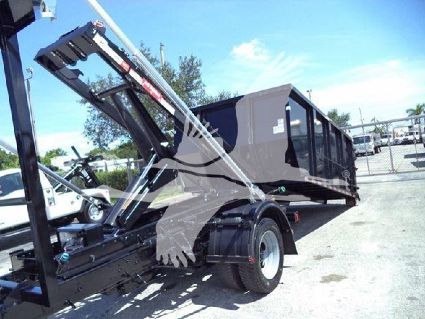 Ford F-550 roll-off truck showing dumping bed and hydraulic hoist system with black container bed and dual rear wheels.
