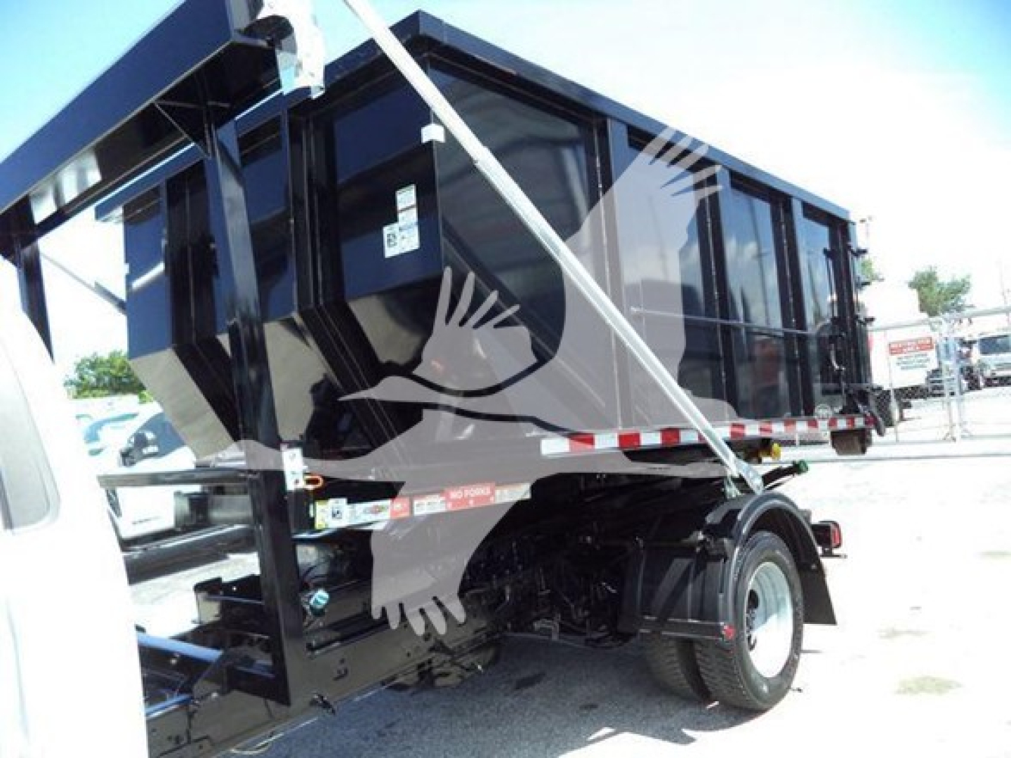 Ford F-550 rolloff truck rear tire and cargo body with hydraulic system and dump bed visible.