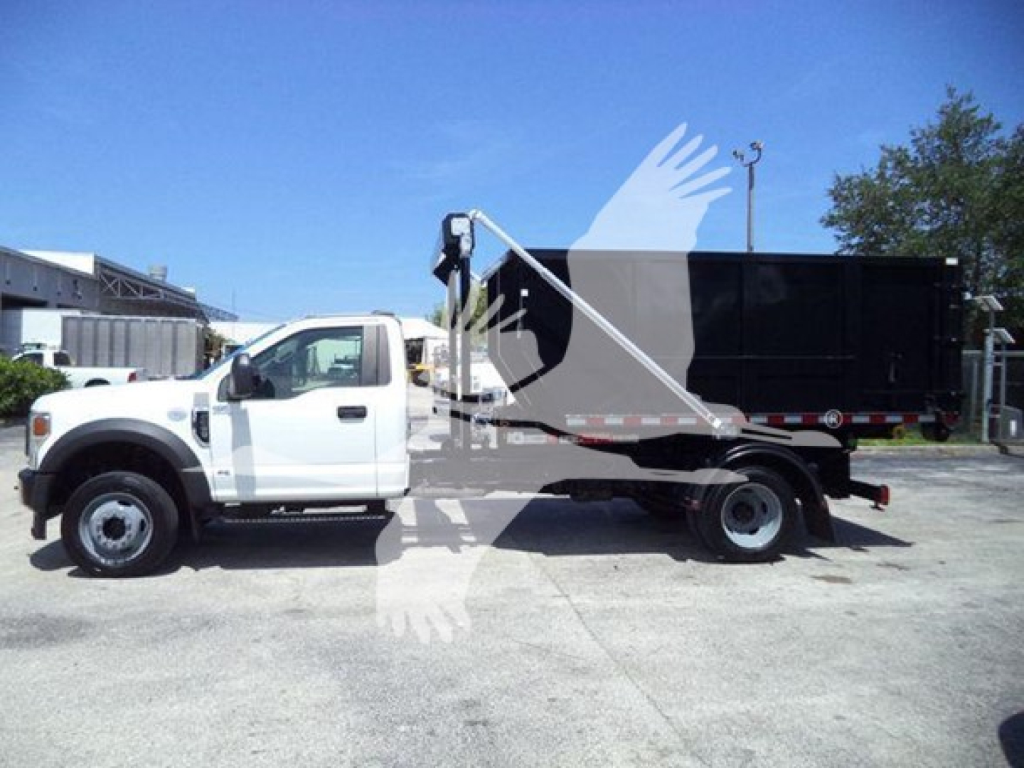 Ford F-550 rolloff truck side view showing dumping bed and cab, white color, VIN 1FDUF5HT7LDA04065.