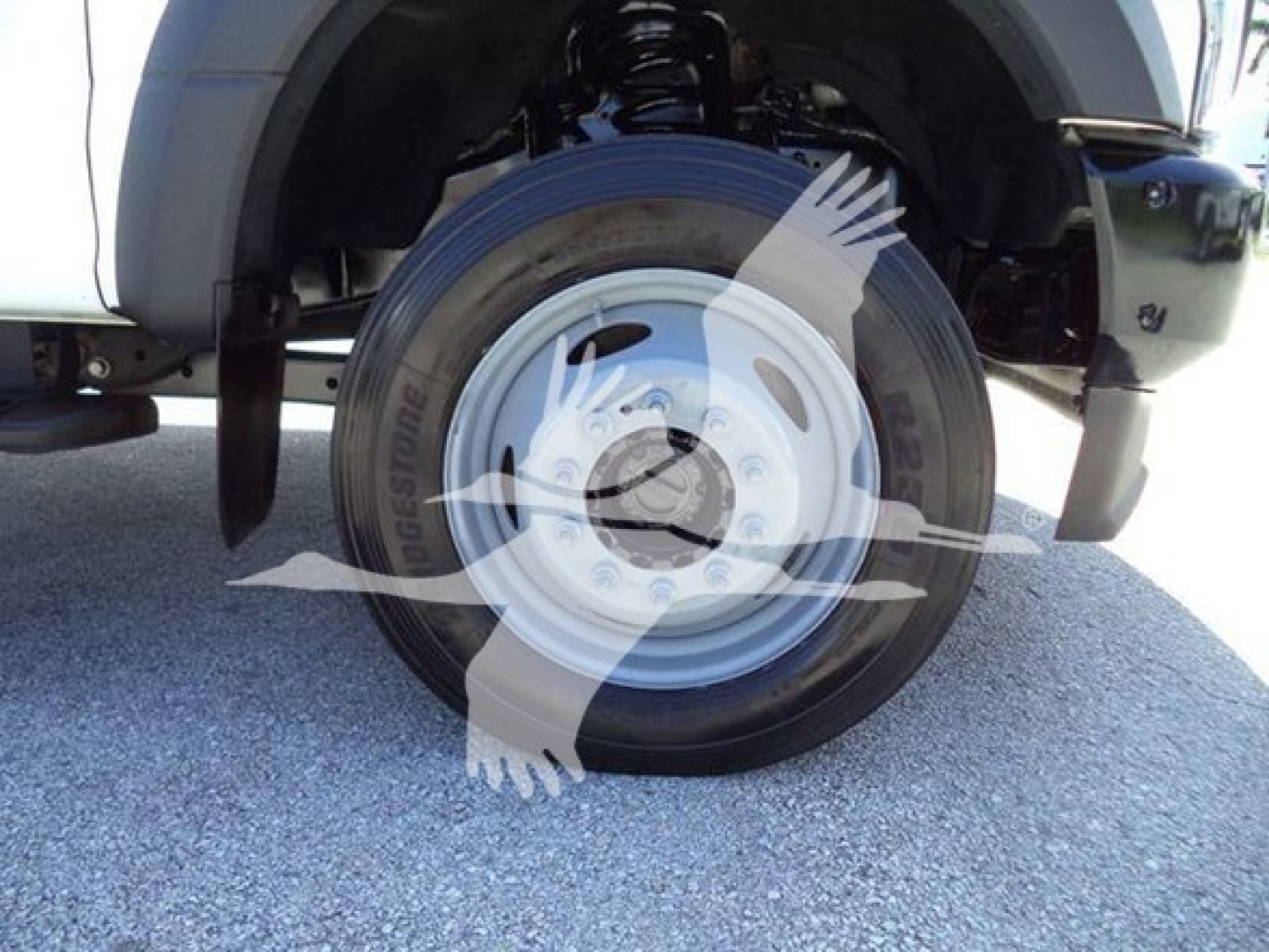 Wheel and front suspension of a 2020 Ford F550 rolloff truck showing steel rim and tire under front fender.