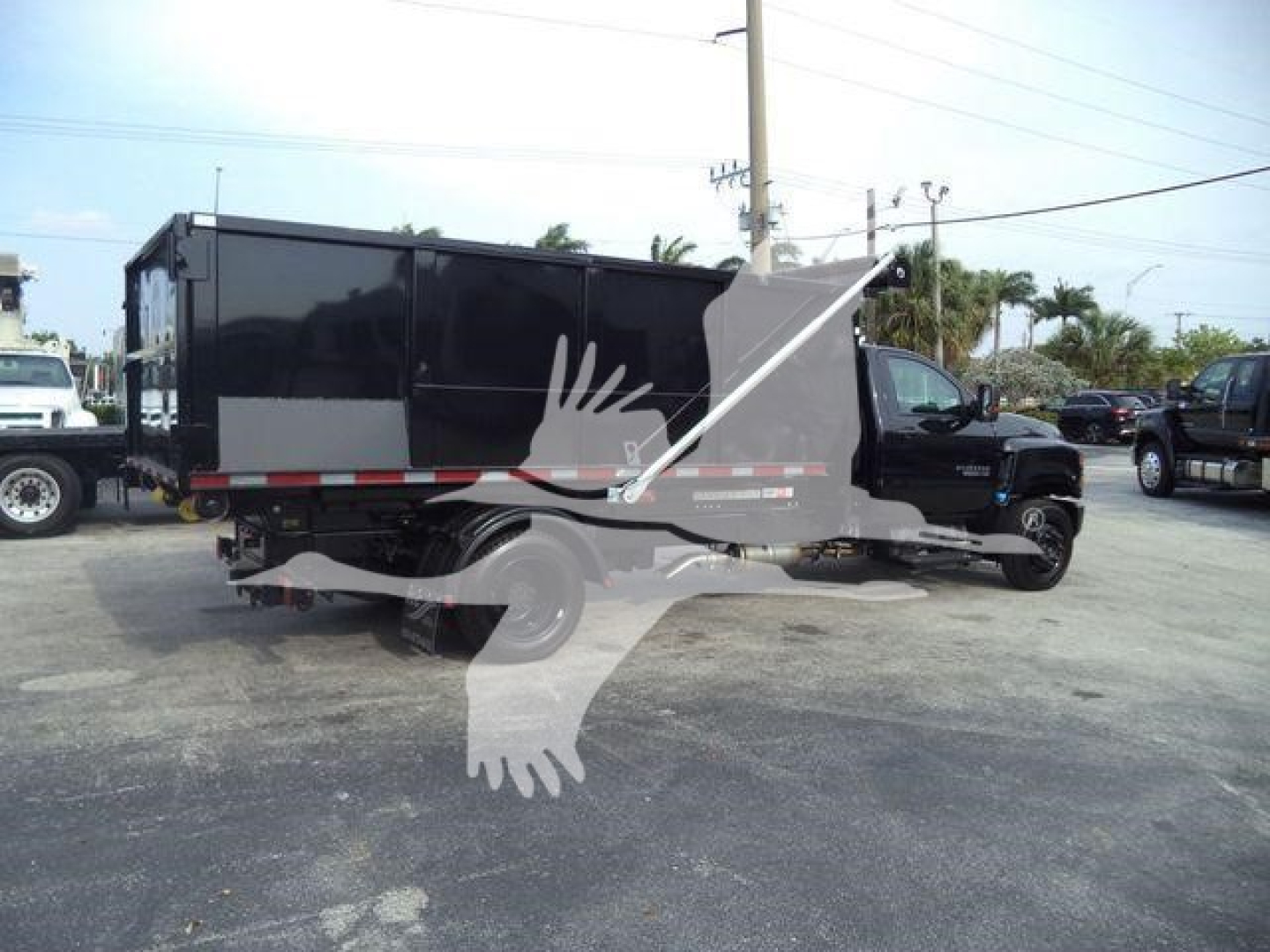 Truck bed and cab of a 2023 Chevrolet Silverado 6500HD rolloff truck side view showing black cargo box and cab details.