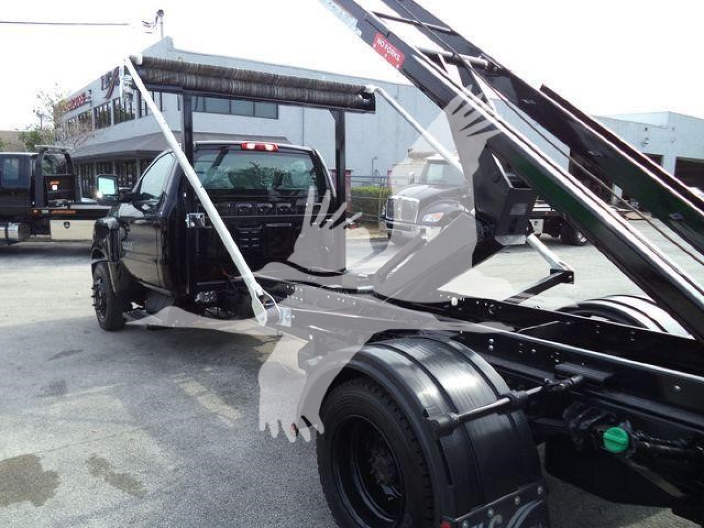 Truck bed with roll-off hoist on a new 2023 Chevrolet Silverado 6500HD showing front cab and hydraulic lifting mechanism.