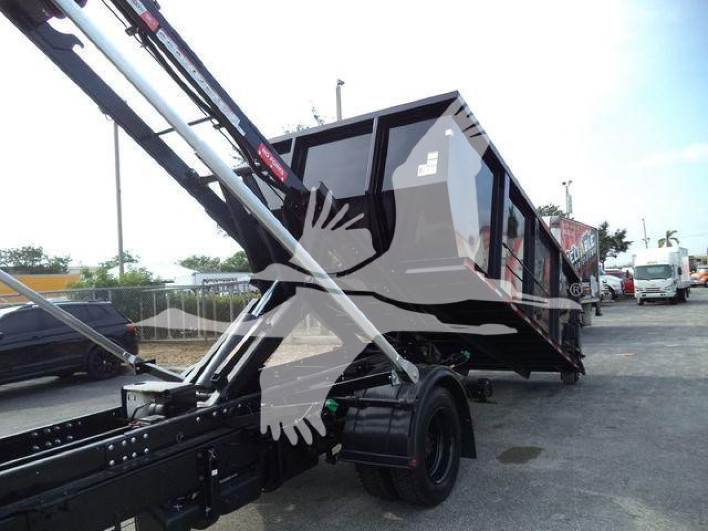 Truck bed showing a roll-off style dump body with hydraulic arms and black chassis.