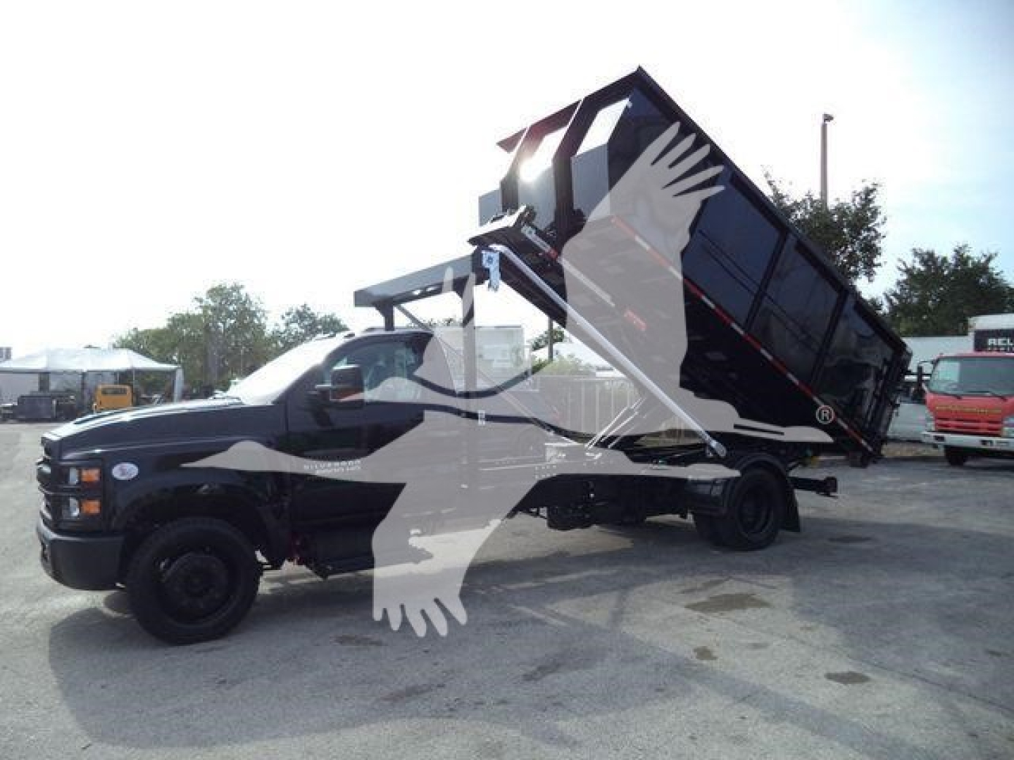 Truck in yard with a dump bed raised at rear, Chevrolet Silverado 6500HD label and stock number J05883FM visible in listing context.