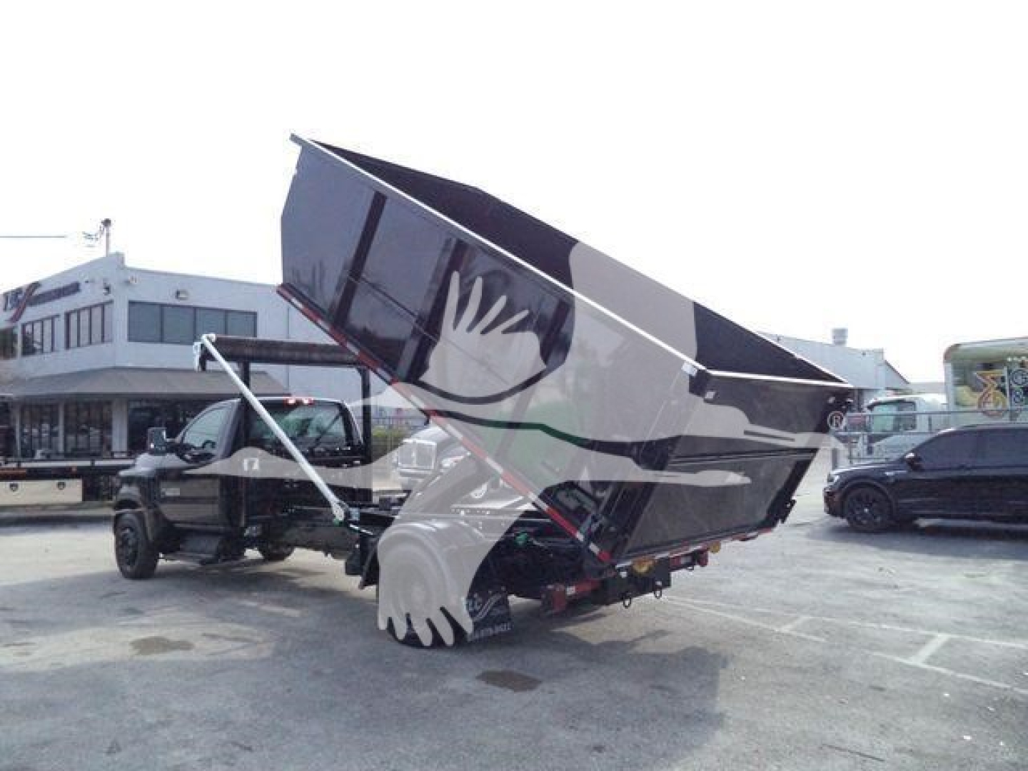 Truck-mounted dump bed on a Chevrolet Silverado 6500HD with the bed raised, displaying the hydraulic mechanism and rear wheels.