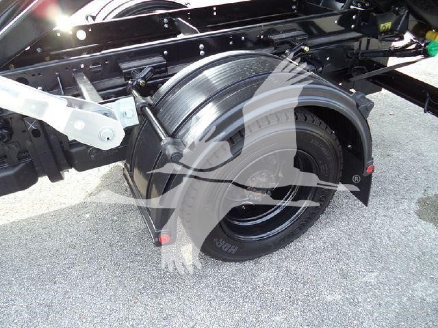 Truck chassis and rear wheel assembly showing wheel, suspension, and rolloff container mounting area on a 2023 Chevrolet Silverado 6500HD.