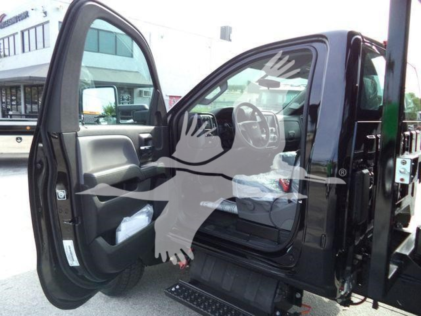 Truck cab interior visible with open driver door showing steering wheel and dashboard, Chevrolet Silverado 6500HD badge implied, image of new roll-off truck.