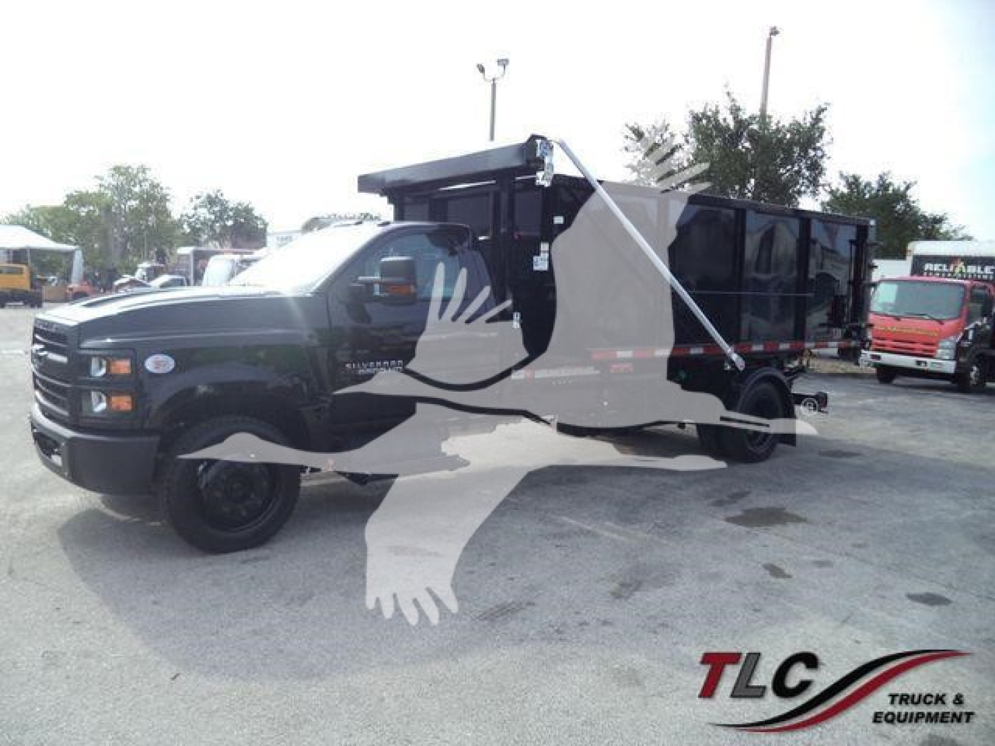 Chevrolet Silverado 6500HD dump truck in a lot, black body, roll-off bed, front grille, side mirrors, and wheel bolts visible.