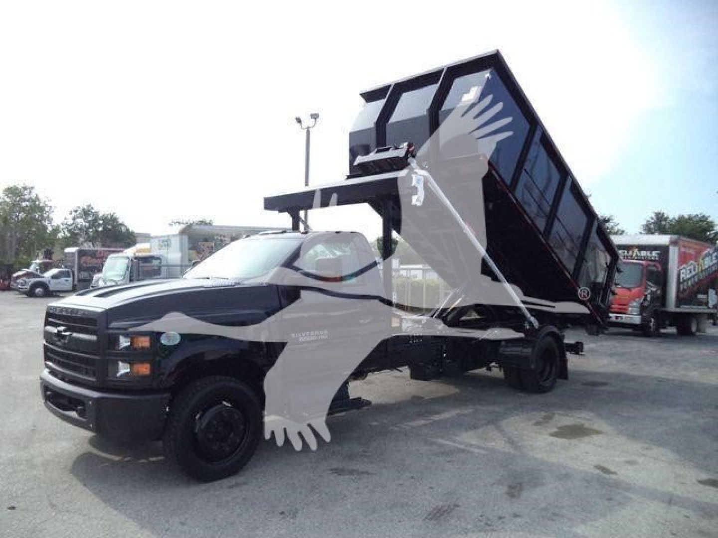 Chevrolet Silverado 6500HD dump truck in tilt bed configuration with raised dump body and black chassis.