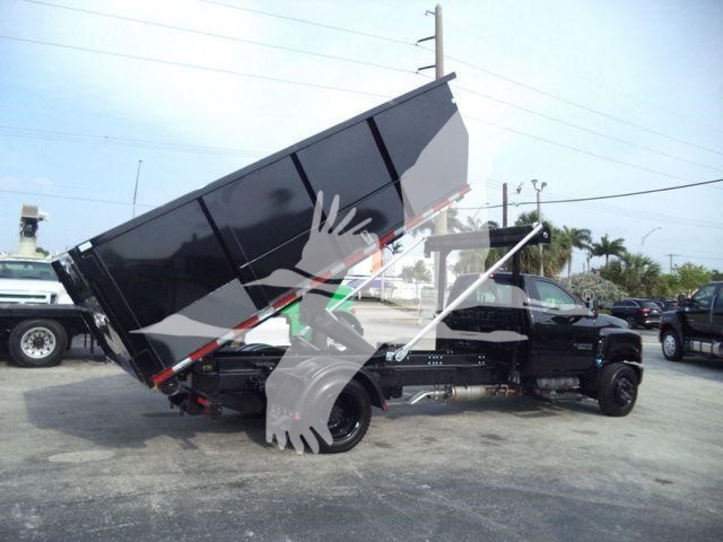 Chevrolet Silverado 6500HD dump truck in raised bed position with dump body on a black chassis viewed from side.
