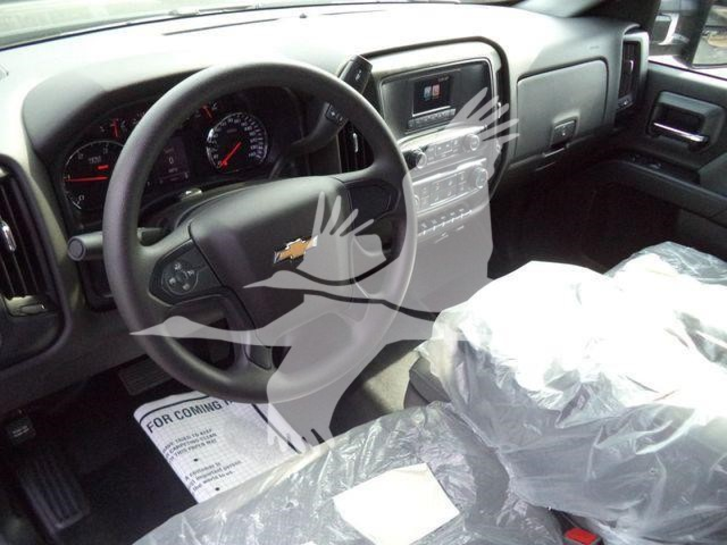 Interior of a 2023 Chevrolet Silverado 6500HD showing steering wheel, dashboard, and center console with plastic-covered seat.