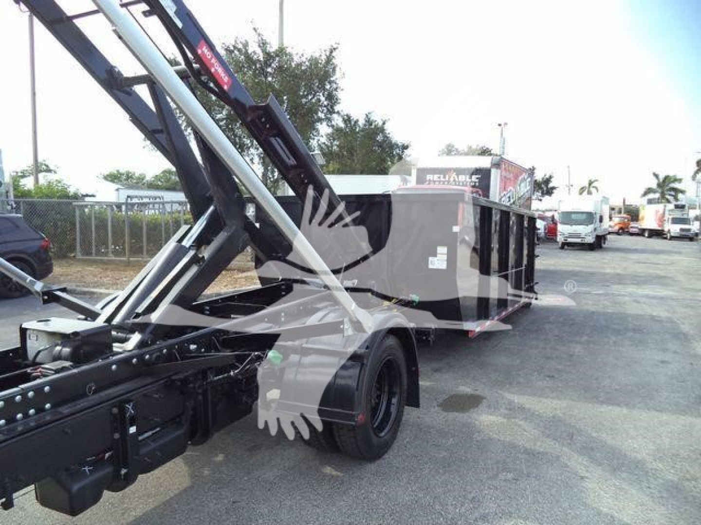Chevrolet Silverado 6500Hd roll-off truck in a lot showing hydraulic arms and rear bed.