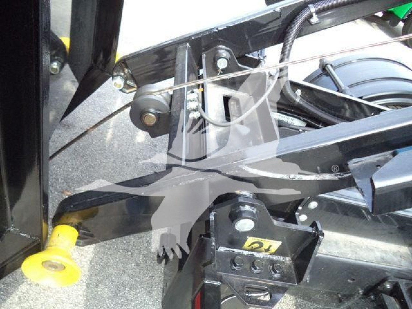 Truck hitch area showing mounting bracket and pin on a Silverado 6500HD roll-off chassis with black metal framework and yellow stabilizer foot.