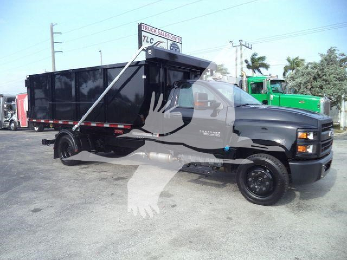 Chevrolet Silverado 6500HD roll-off truck in black with a dump bed, side view showing stamped cab details