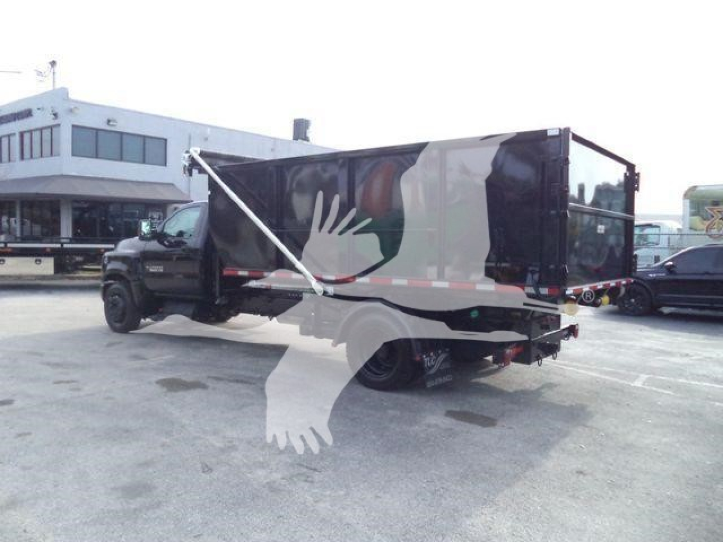 Chevrolet Silverado 6500HD roll-off truck in a parking lot showing side view with dump bed and branding