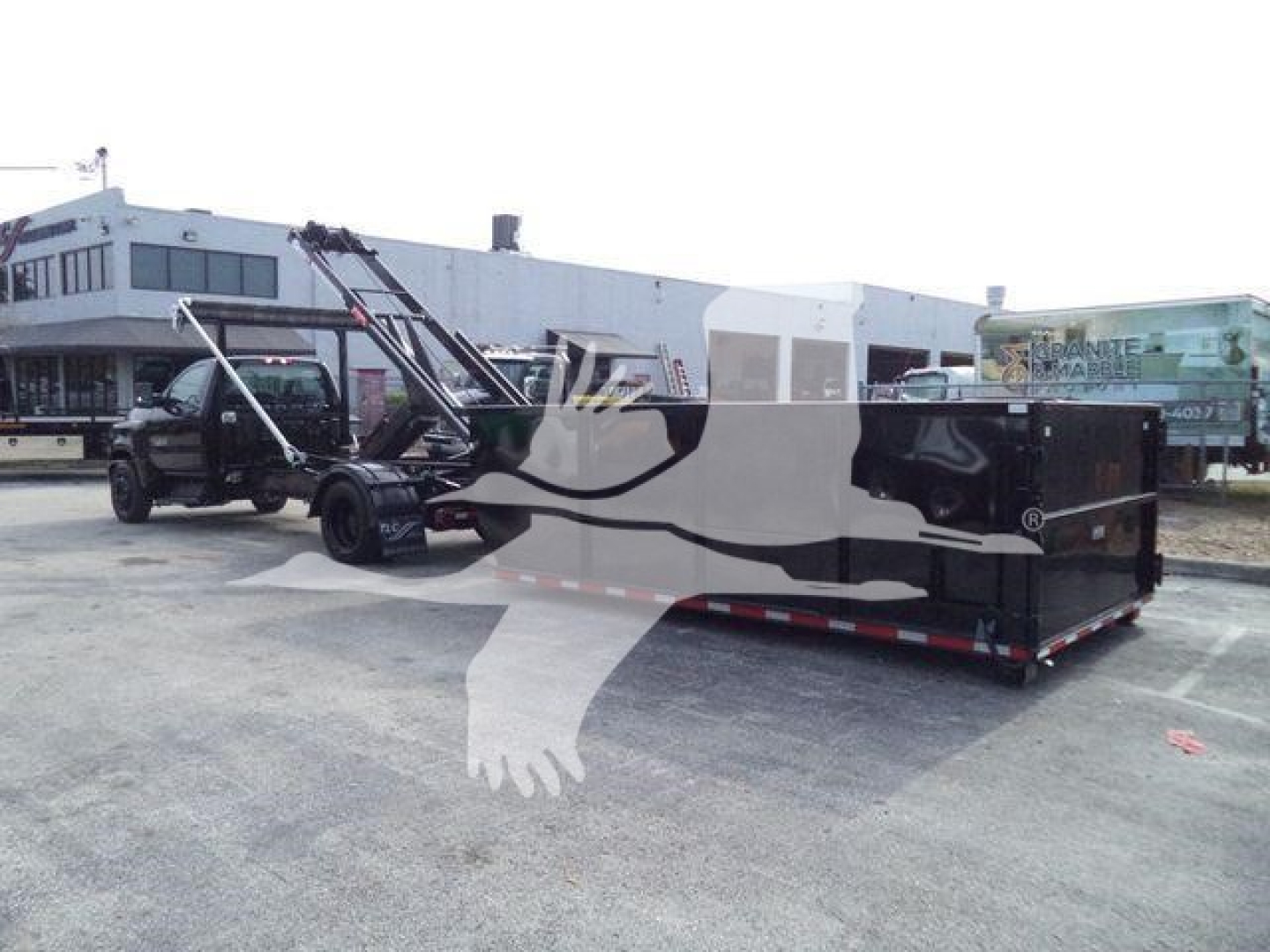 Chevrolet Silverado 6500HD roll-off with black-and-gray module in a parking lot, truck in background, stock number J05883FM