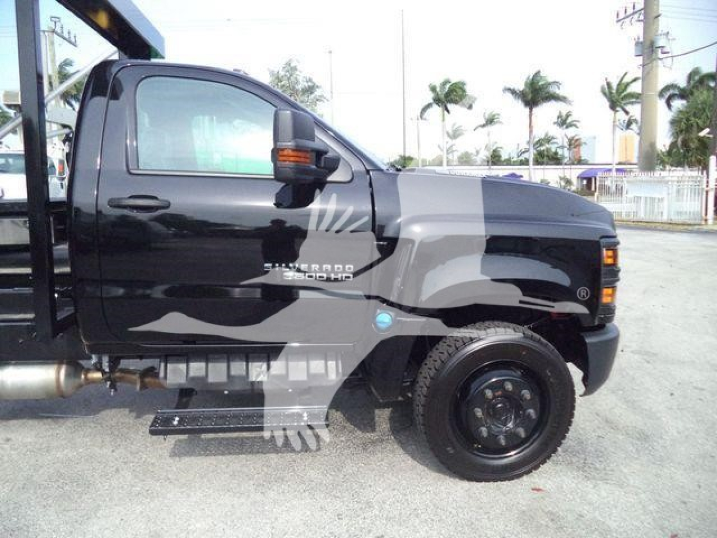 Truck side view showing 2023 Chevrolet Silverado 6500HD roloff truck cab with black paint and decals.