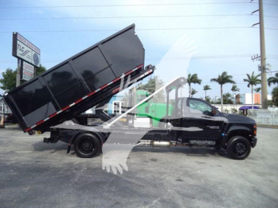Truck side view of a 2023 Chevrolet Silverado 6500HD with a raised dump bed in a dealership lot.
