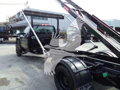Truck bed with roll-off hoist on a new 2023 Chevrolet Silverado 6500HD showing front cab and hydraulic lifting mechanism.