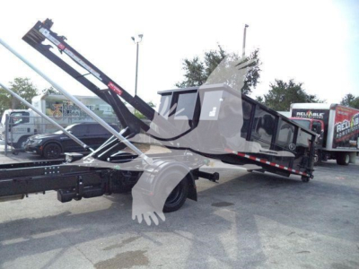 Truck bed with rollback mechanism and dual hydraulic arms showing a Chevrolet Silverado chassis in a service lot