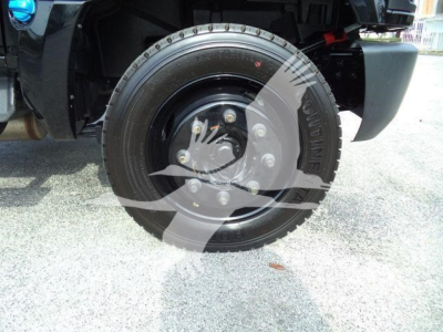 Wheel and tire on front of 2023 Chevrolet Silverado 6500HD dump truck showing steel wheel, lug nuts, and tire with tread, fender and part of suspension visible.