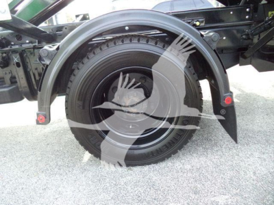 Wheel well and tire on a 2023 Chevrolet Silverado 6500HD rolloff truck showing fender and suspension components.