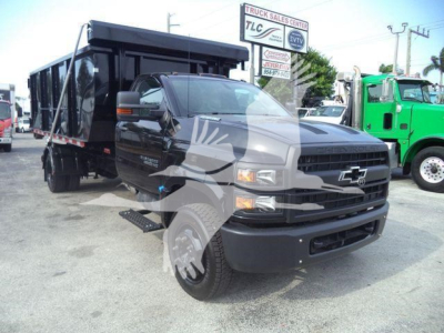 2023 Chevrolet Silverado 6500HD dump truck side front view showing black dump bed and front grille with Chevrolet emblem.