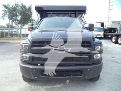 Front view of a 2023 Chevrolet Silverado 6500HD dump truck, black grille with bowtie emblem, large bumper, side mirrors, and dump bed visible in background.