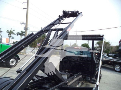 Truck rear with hydraulic arms and roll-off system showing chassis and control area.