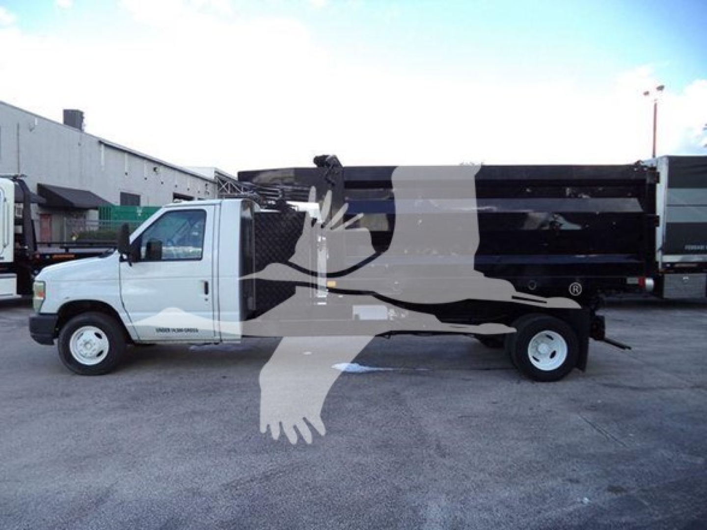 Truck side view of a 2011 Ford E450 dump truck showing cargo bed and wheels with stock number T20696 visible.