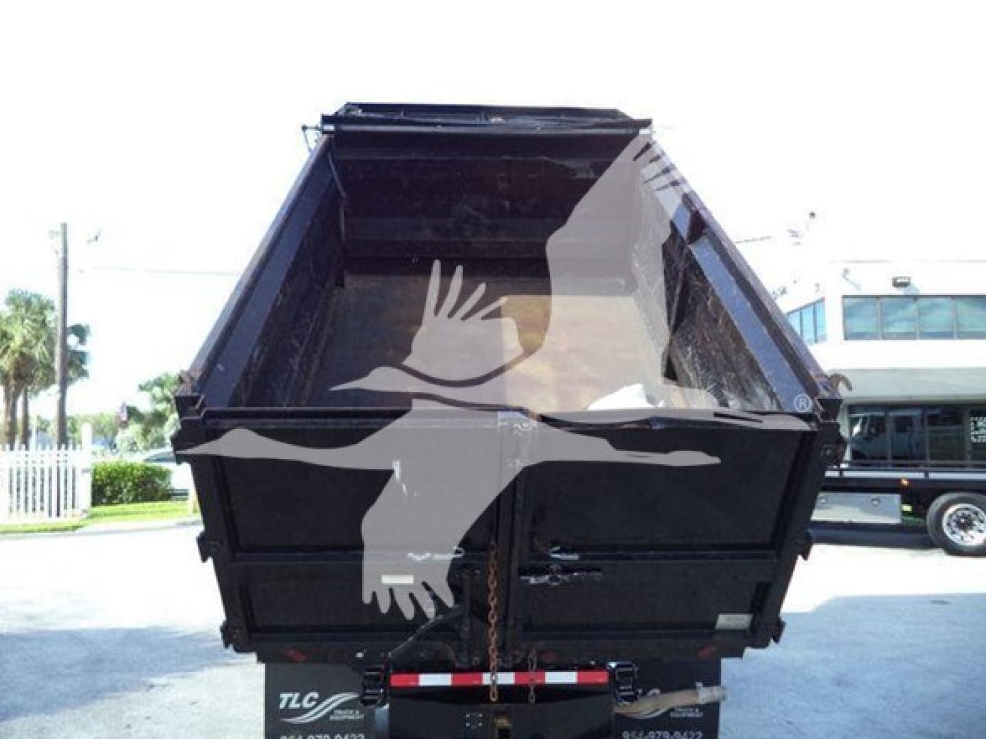 Dump truck bed in back of a Ford E450 dump truck with open tailgate and logo watermark across image.
